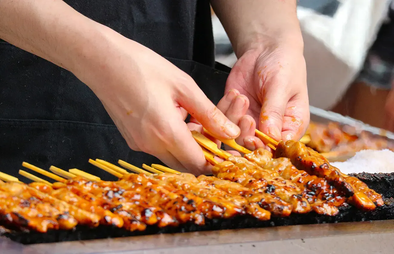 A chef grilling delicious meat skewers on a hot barbecue at the Suncoast Food & Wine Fest.