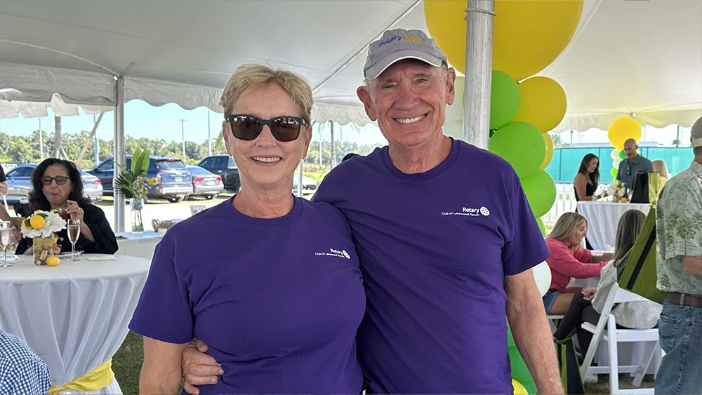 Two Rotary Club of Lakewood Ranch members smiling together in purple shirts at the festival.