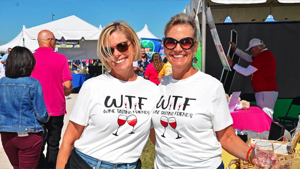 Two women wearing matching Wine Tasting Friends t-shirts at the Suncoast Food & Wine Fest.