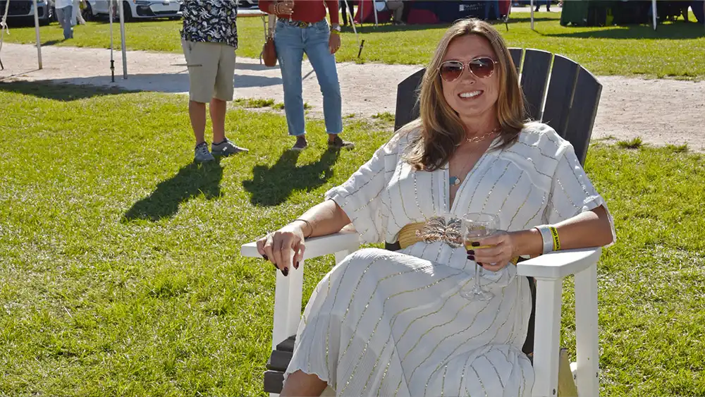 A woman in a white dress relaxing in an Adirondack chair at the Suncoast Food & Wine Fest.